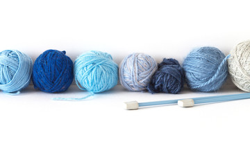 The balls of different shades of blue wool and acrylic yarn for hand knitting lie in a row on a white background. Bottom and top empty space for text. Ckjseup, copy space