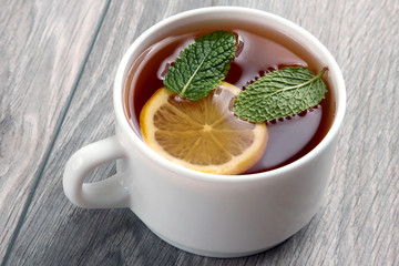 white tea cup with lemon and mint on wooden table