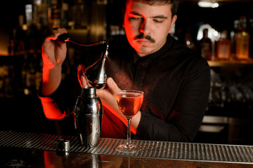 Professional bartender spraying from the diffuser on the delicious cocktail in the glass