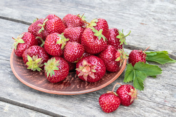 a bowl full of fresh red strawberries on old boards.