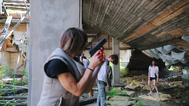 A zombie attack on the top floor of abandoned building. Survived woman with a gun hiding behind a column from zombies