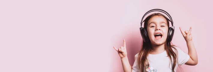 Poster Cute little girl listening music wearing headphones. © paninastock