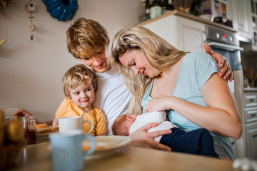 Young parents with newborn baby and small toddler son at home.