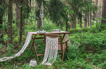 Boho style wedding reception dinning table with macrame tablecloth, decoration on a rustic wooden table