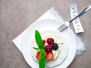 Pavlova meringue cake with fresh berries on white plate with inscription, top view
