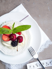 Pavlova meringue cake with fresh berries on white plate with inscription, top view