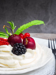 meringues pavlova cake with fresh cherry, blackberry, strawberry on concrete background