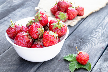 bowl full of fresh strawberries on wooden background.