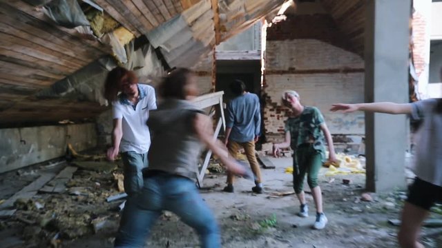 A zombie attack in abandoned building. Survived woman running with a gun avoiding attack of zombies