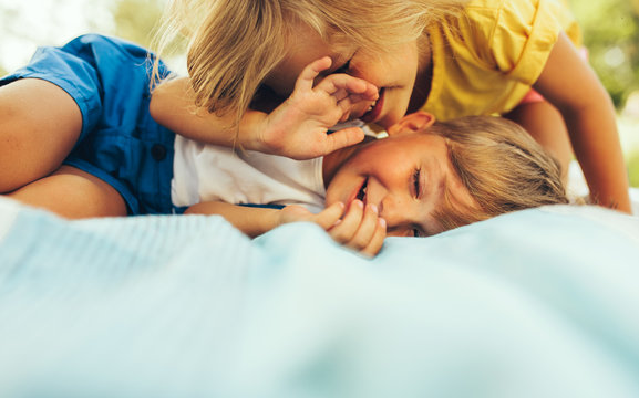 Closeup image of happy children playing on the blanket outdoors. Happy little boy and cute little girl relaxing in the park. Kids having fun on sunlight. Sister and brother spending time together