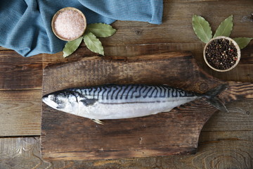 Fresh mackerel with salt, pepper and bay leaves on a wooden cutting board and wooden rustic...