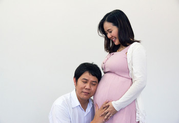 Close-up husband listening sound baby from Pregnant woman and white color background.