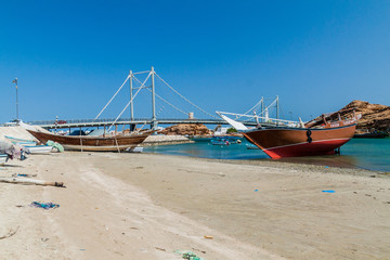 Fototapeta na wymiar Traditional dhow boat yards in Sur, Oman. Khor al Batar bridge in the background.