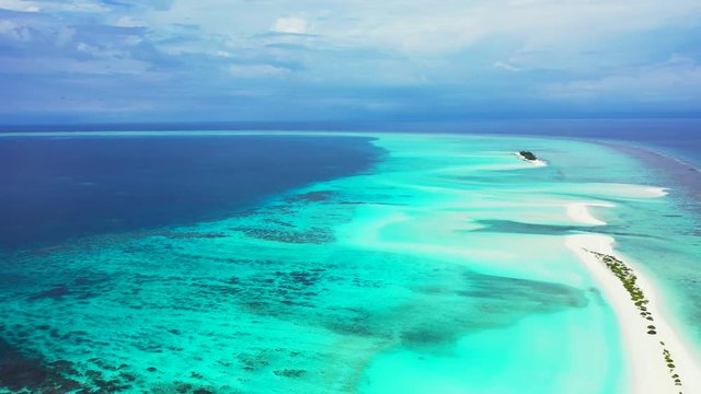 Aerial view of a long and thin sandbank with scrubs on it. In the Caribbean Sea. Slow dolly out and truck right, wide angle.