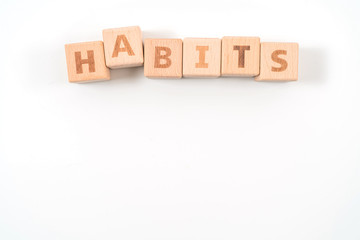 word HABITS on wood cube dices on white background.