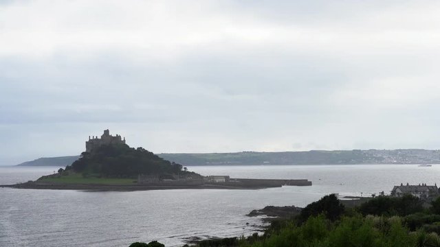 View from a terrace in Marazion of the english medieval castle and church of St Michael's Mount in Cornwall on a cloudy spring day.Zoom in 4k footage