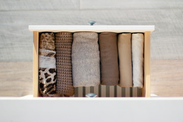 warm brown clothes neatly folded in a drawer white wooden chest, top view