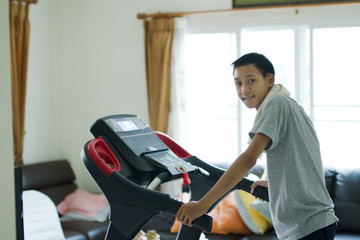 Healthy Young asia man smiling with happy face while running on a machine at home