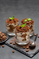 Classic tiramisu dessert in a glass on stone serving board on dark concrete background