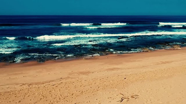 Aerial footage filmed with a drone overlooking the beach and sea of crashing waves with a deep blue ocean on the Bluff in Africa southern hemisphere.