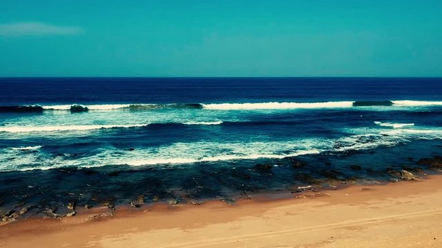 Aerial footage filmed with a drone overlooking the beach and sea of crashing waves with a deep blue ocean on the Bluff in Africa southern hemisphere.