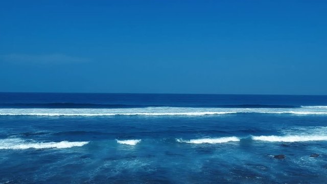 Aerial footage filmed with a drone overlooking the beach and sea of crashing waves with a deep blue ocean on the Bluff in Africa southern hemisphere.