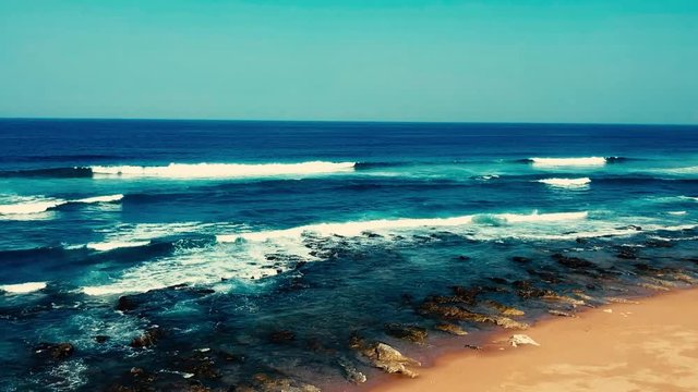 Aerial footage filmed with a drone overlooking the beach and sea of crashing waves with a deep blue ocean on the Bluff in Africa southern hemisphere.