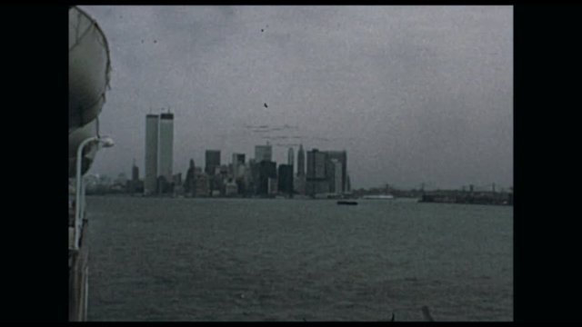 A vintage film shot looking back from a boat toward the New York City skyline from the 1970s.