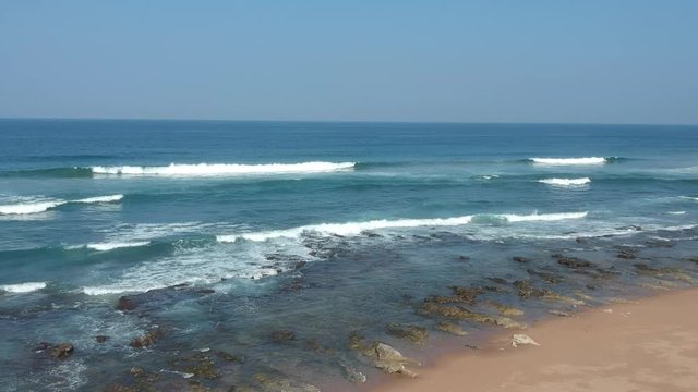 Aerial footage filmed with a drone overlooking the beach and sea of crashing waves with a deep blue ocean on the Bluff in Africa southern hemisphere.