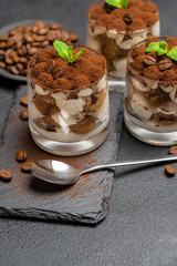 Classic tiramisu dessert in a glass on stone serving board on dark concrete background