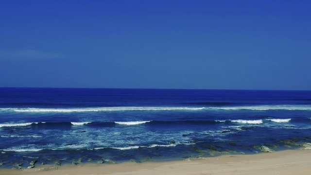 Aerial footage filmed with a drone overlooking the beach and sea of crashing waves with a deep blue ocean on the Bluff in Africa southern hemisphere.