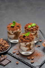 Classic tiramisu dessert in a glass on stone serving board on dark concrete background