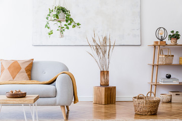 The stylish boho compostion at living room interior with design gray sofa, wooden coffee table, bamboo shelf and elegant personal accessories. Honey yellow pillow and plaid. Cozy apartment. Home decor