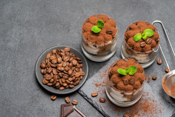 Classic tiramisu dessert in a glass on stone serving board on dark concrete background
