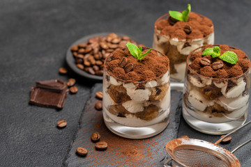 Classic tiramisu dessert in a glass on stone serving board on dark concrete background