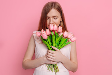 Happy girl in summer dress holding a bouquet of flowers in hand