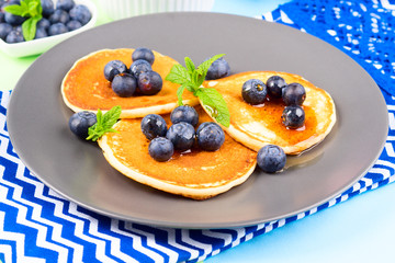 Pancakes served with fresh blueberries on gray plate over geometrical background. Healthy home made breakfast concept