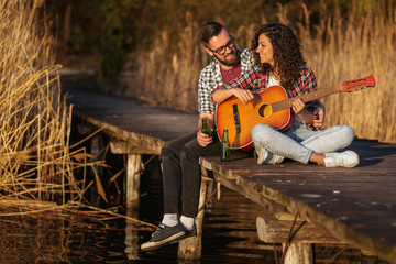 Couple playing the guitar and drinking beer