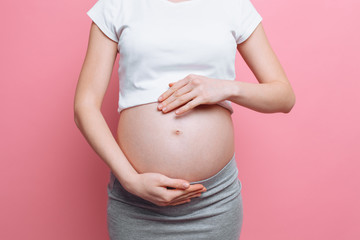 Pregnant woman holding belly with love, third trimester
