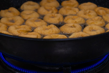 Donuts fritter making machine, handmade, frying sweet and tasty donuts in hot oil in a pan