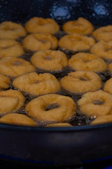 Donuts fritter making machine, handmade, frying sweet and tasty donuts in hot oil in a pan