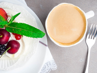 Dessert pavlova meringue with whipped cream and mint leaf decoration and cup of coffee