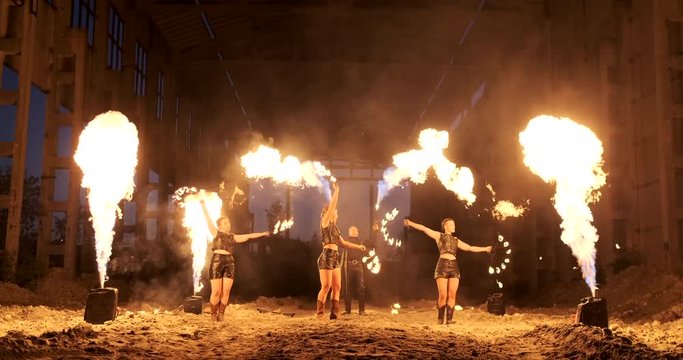 A group of professional artists with fire show the show juggling and dancing with fire in slow motion.