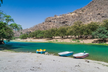 Fototapeta na wymiar Boats at a small lake at Wadi Dharbat near Salalah, Oman.