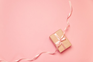 Flat lay top view crafting paper gift on pink background. Minimalism concept. Holiday banner.