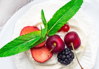 meringues pavlova cake with fresh cherry, blackberry, strawberry on concrete background
