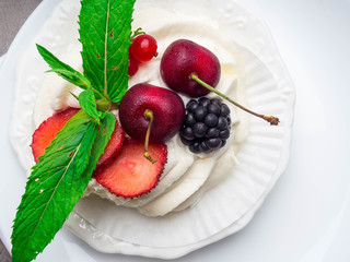 meringues pavlova cake with fresh cherry, blackberry, strawberry on concrete background
