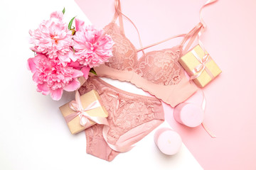 Female elegant pink lace bra and panties, flowers pink candles, a bouquet of beautiful peonies top view