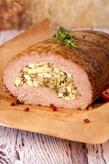 Meatloaf stuffed with eggs and fried onions. A large portion of meat is cut and served in a rustic style. .Close up and vertical orientation.