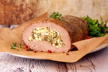 Meatloaf stuffed with eggs and fried onions. A large portion of meat is cut and served in a rustic style. .Close up and horizontal orientation.